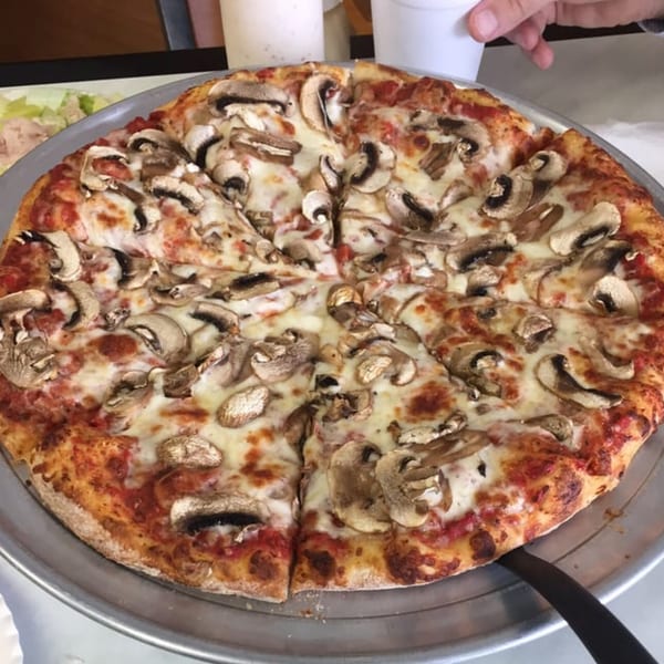 A whole mushroom pizza from Jack's Pizza & Subs, sliced and ready to serve on a metal tray.