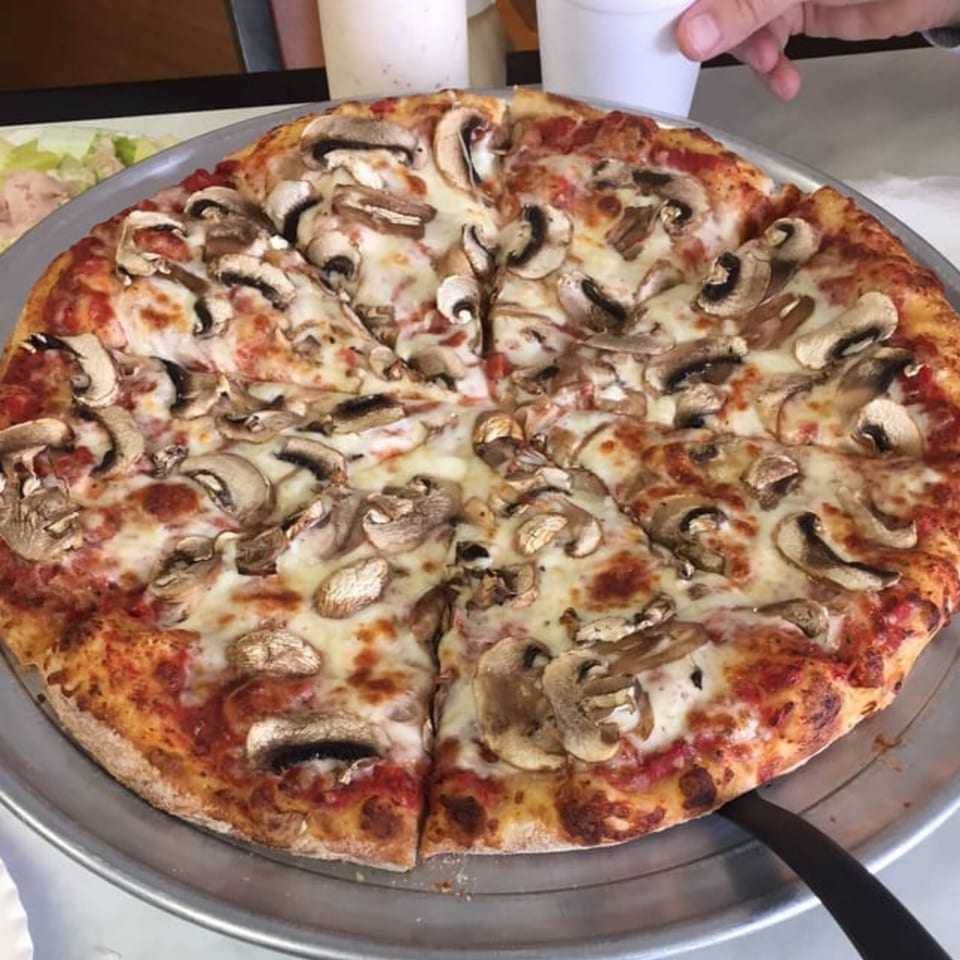 A whole mushroom pizza from Jack's Pizza & Subs, sliced and ready to serve on a metal tray.
