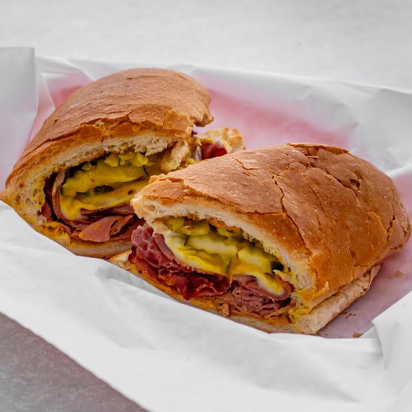 A Jack's Pizza & Subs sub sandwich, sliced in half, with meat, cheese, and pickles.