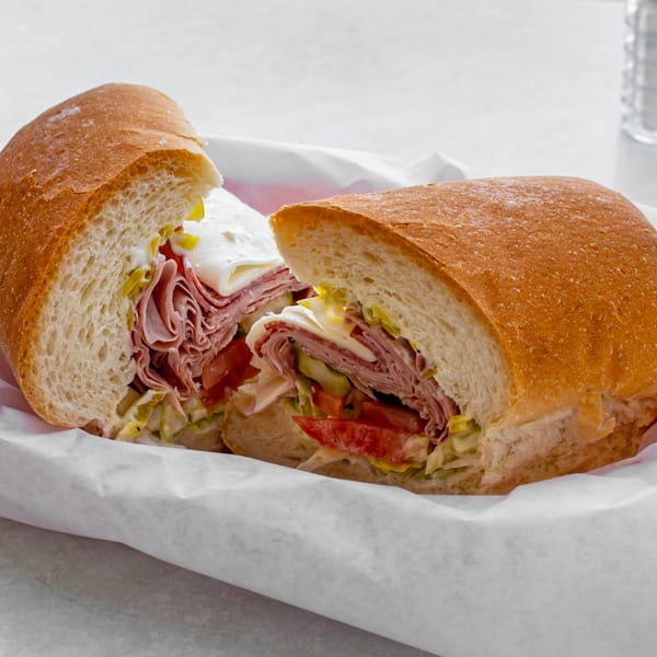 A Jack's Pizza & Subs sub sandwich, cut in half, filled with meat, cheese, lettuce, and tomatoes.